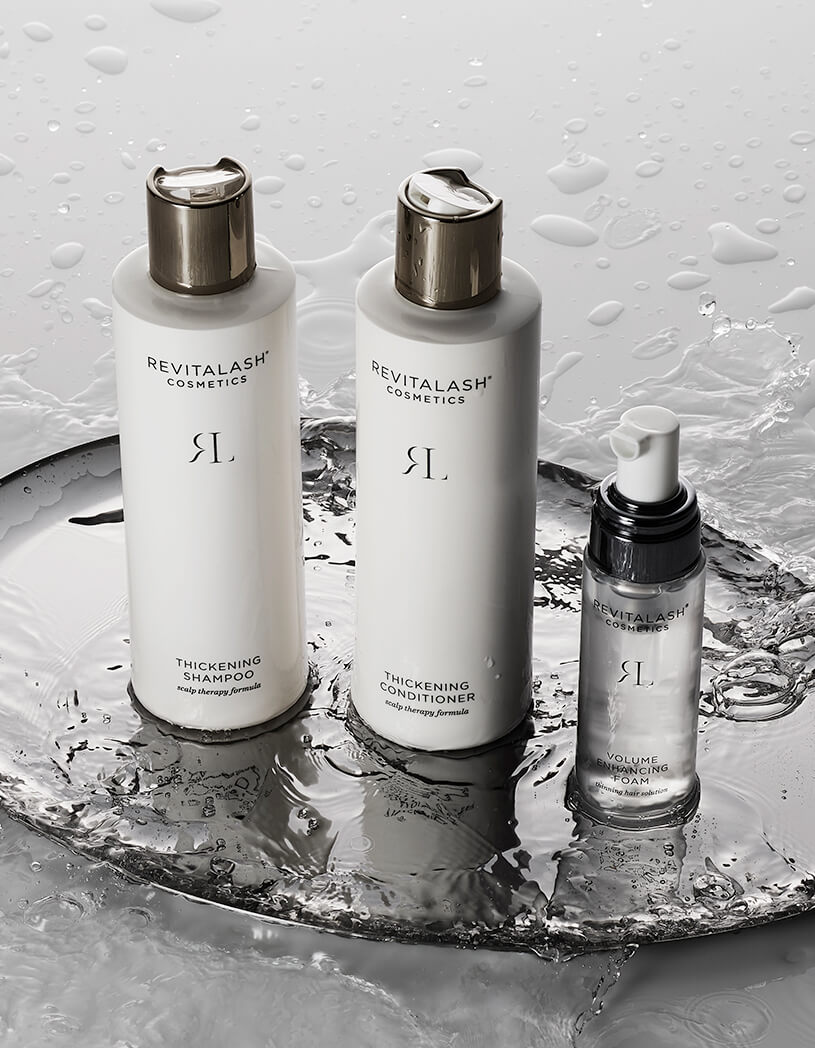 Revitalash cosmetic products on a metallic surface with water droplets.