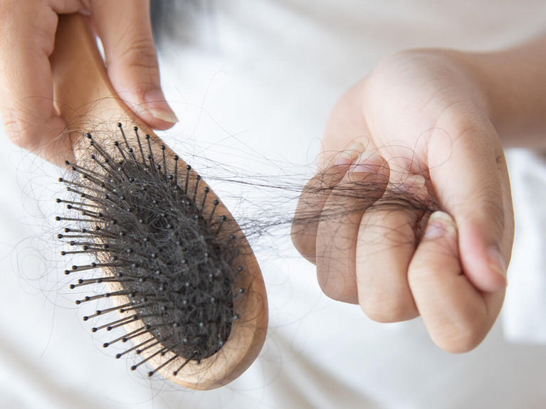 Woman pulling hair off of hairbrush