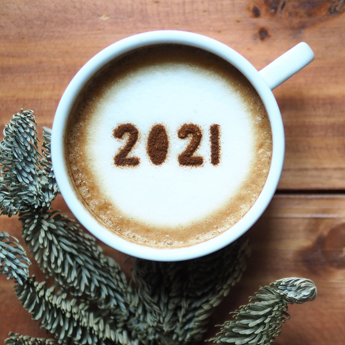 Image of the top of a coffee mug filled with coffee and "2021" written in foam