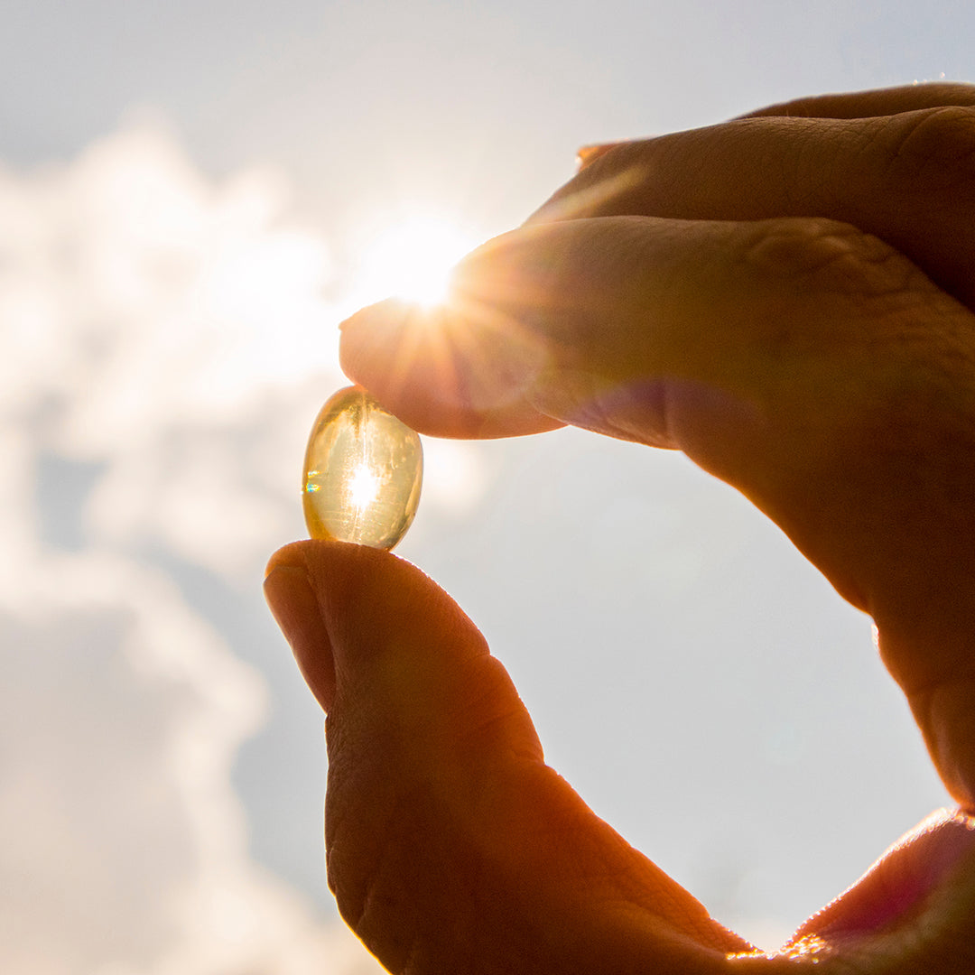 Image of a hand holding a vitamin up to the sunlight