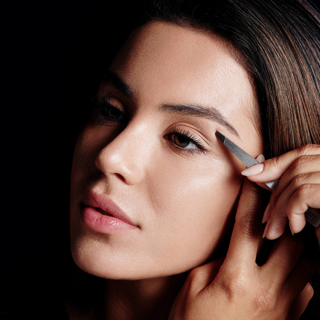 Image of model using RevitaLash Cosmetic's Precision Tweezers to tweeze her eyebrows