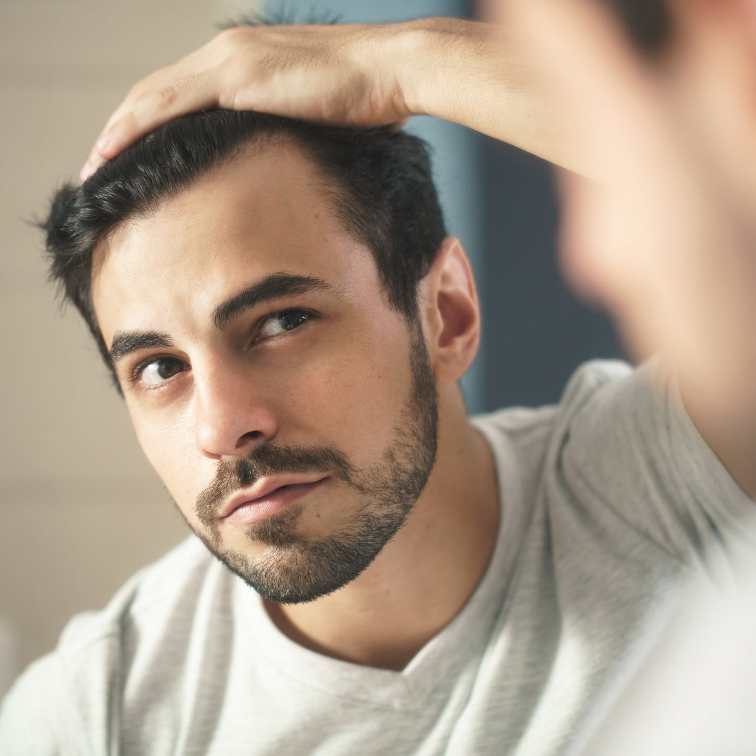 Image of man looking at hairline in the mirror