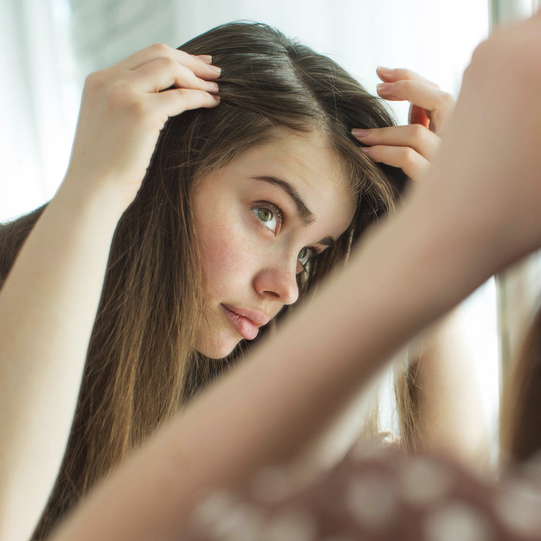 Image of woman examining her hair line in the mirror