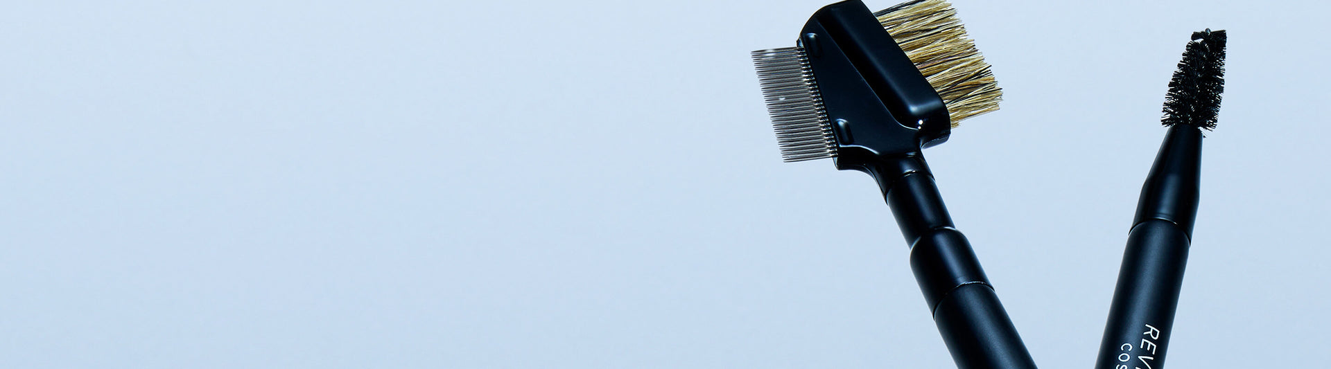 Two black brushes with bristle heads on a light blue background