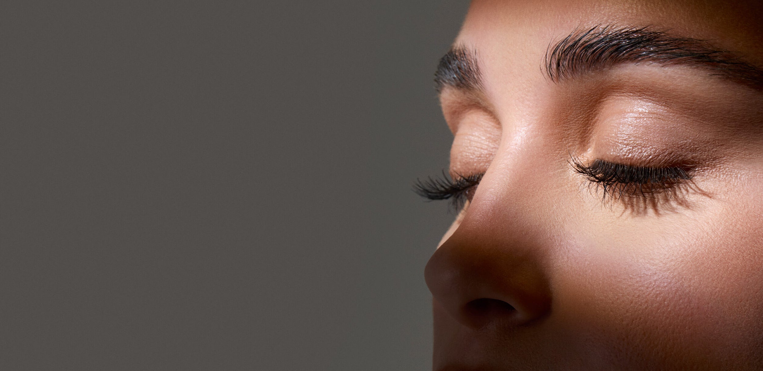Close-up of a woman's face with closed eyes on a dark background