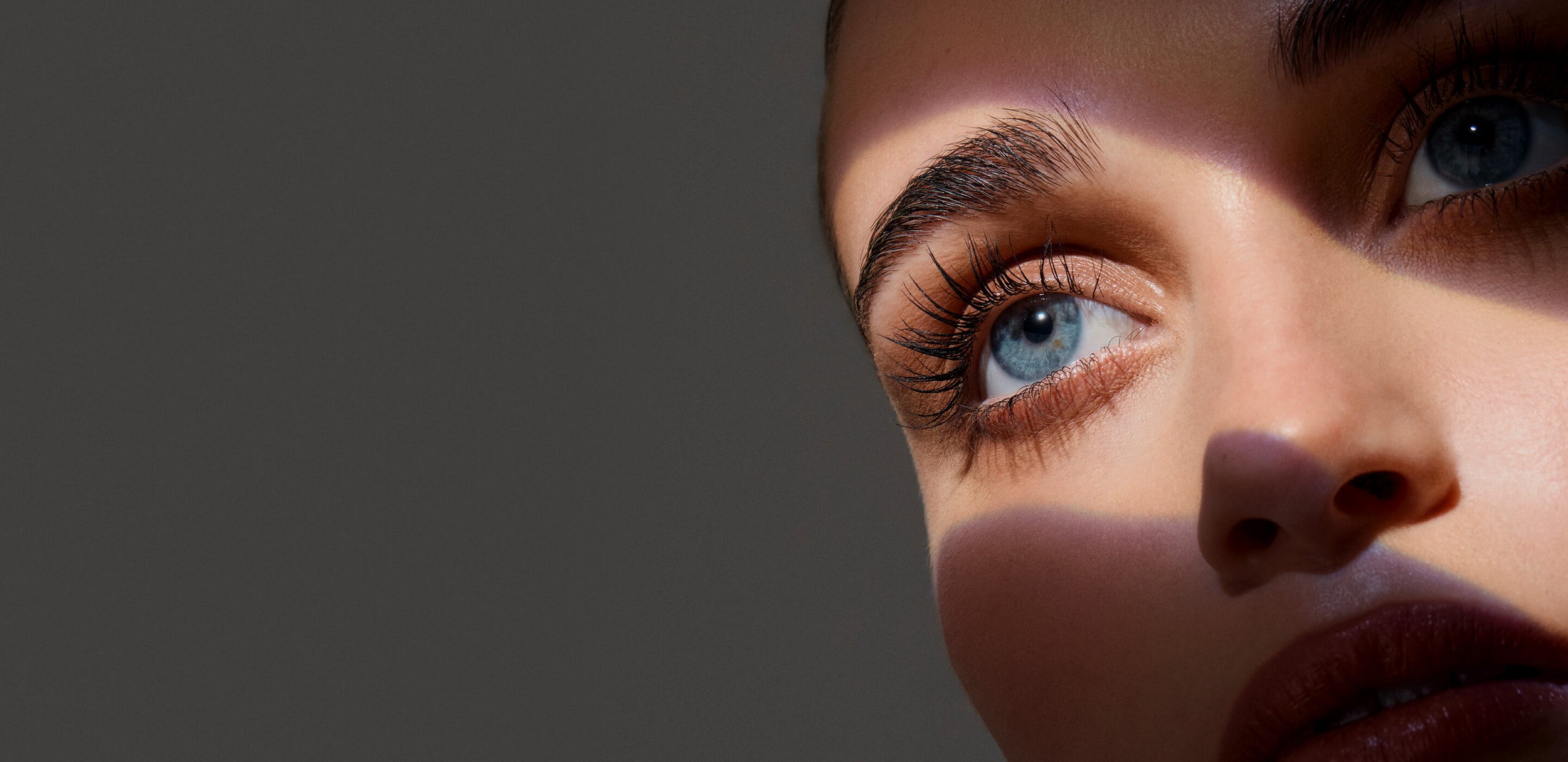 Close-up of a person's eye with a dark background. Model is actual RevitaLash® Cosmetics user. 25% off sitewide $100 purchase.