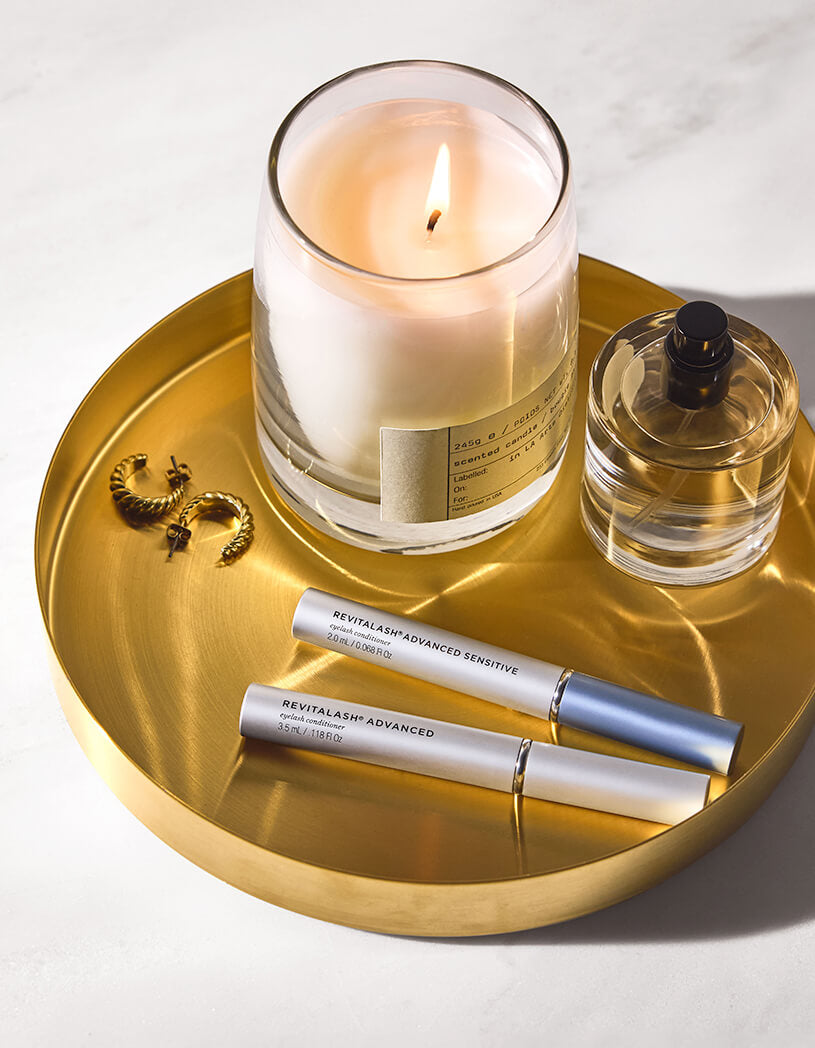 Candle, perfume bottle, and RLA and RLAS on a gold tray with a white background