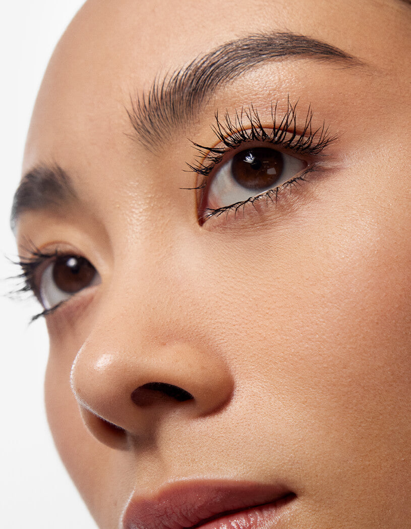 Close-up of a person's eye with detailed makeup on a neutral background