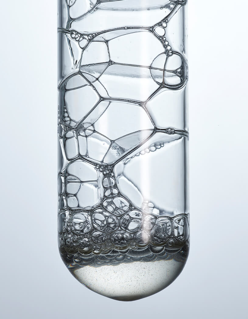 Close-up of a glass with soap bubbles on a light gray background