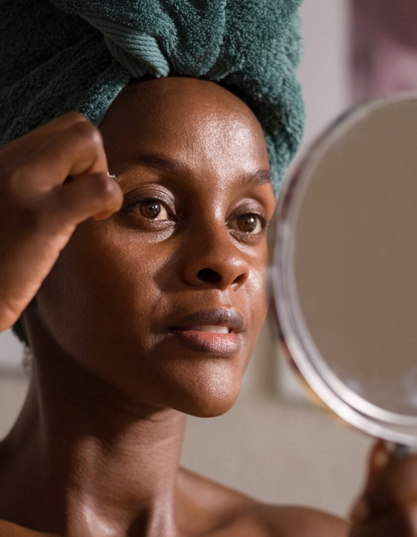 woman plucking her brows looking in the mirror