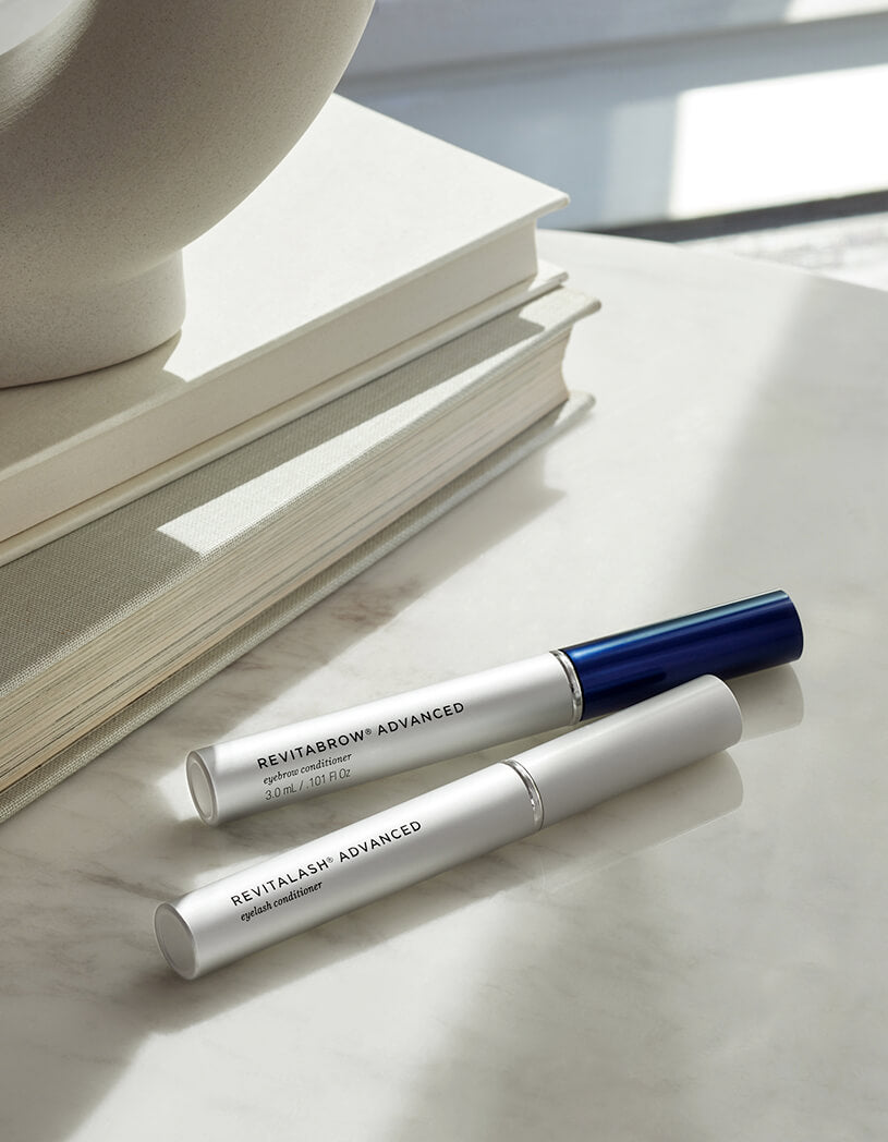 Two RevitaLash Cosmetic products on a light surface with books in the background.
