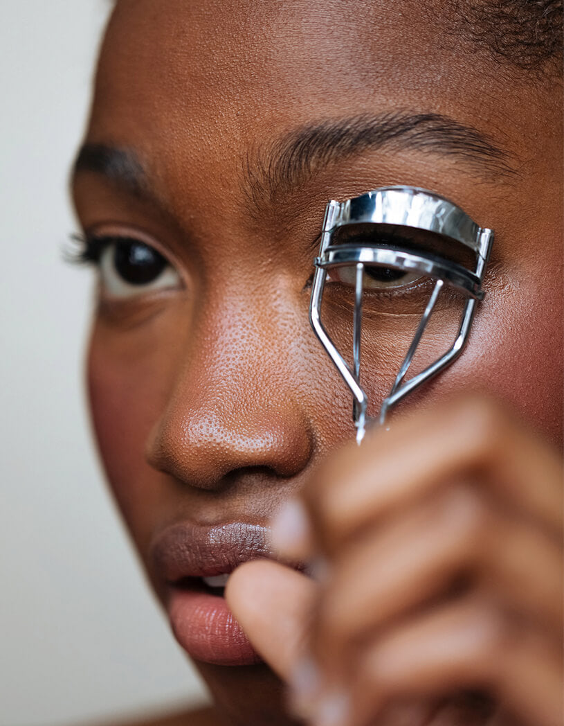 Person using a silver eyelash curler on their eye