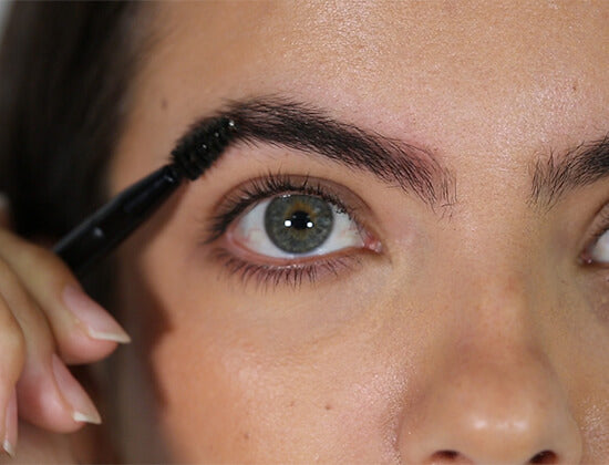 Close-up of a person applying mascara to their eyelashes.