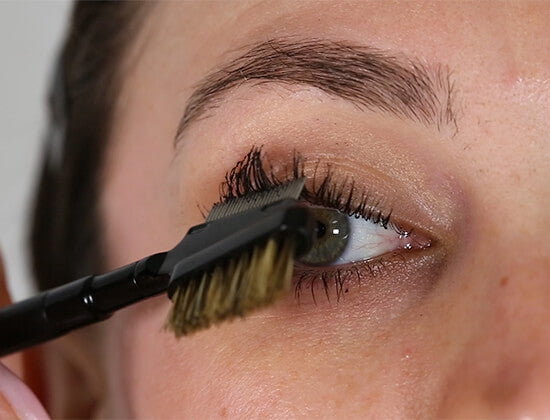 Close-up of a person applying eyeliner with 3-in-1 grooming tool.