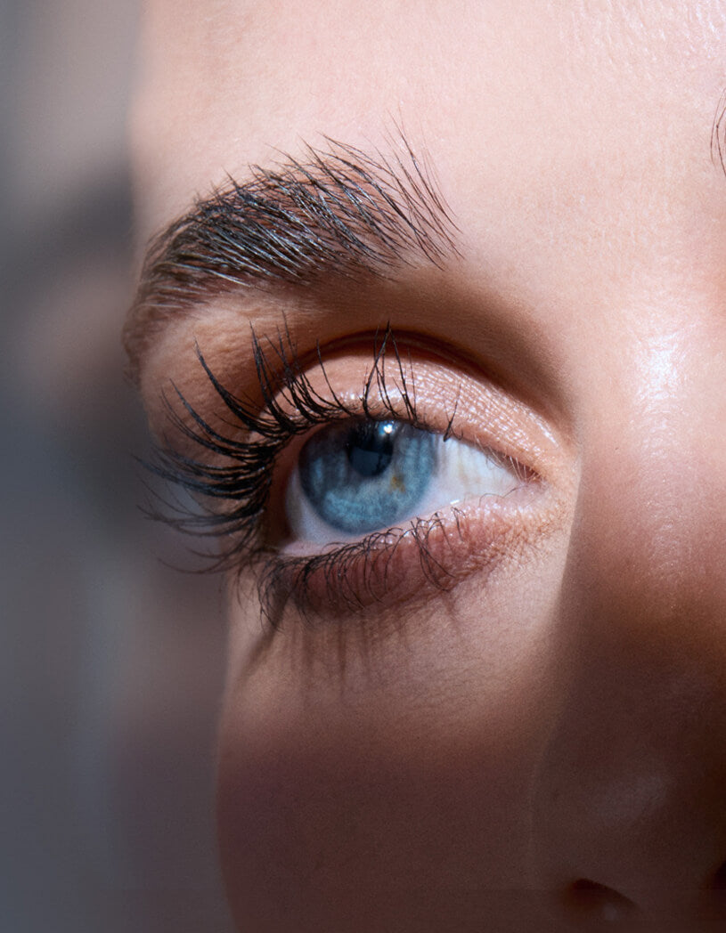 Close-up of a person's eye with blue irises and brown eyelashes.