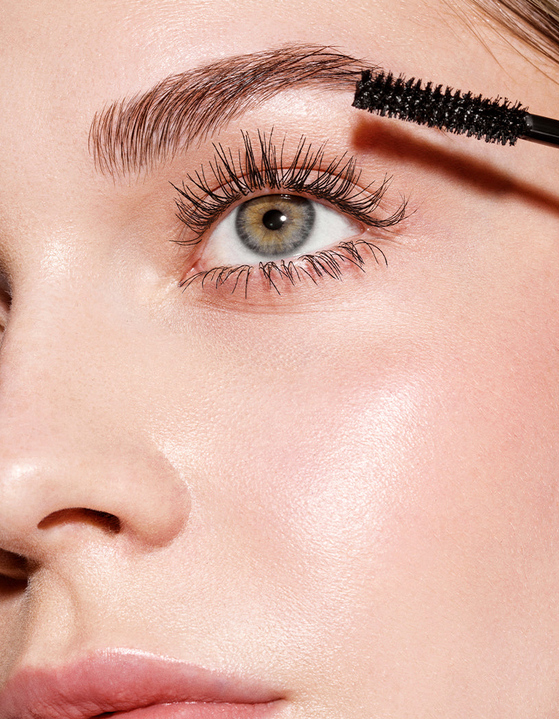 Close-up of a person applying mascara to their eyelashes.