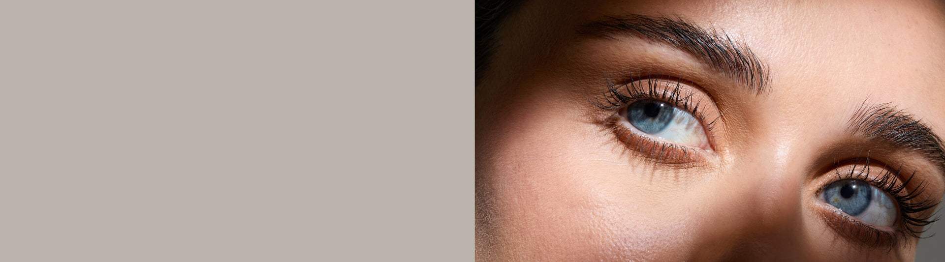Close-up of a person's eyes with detailed eyelashes on a neutral background. Model is actual RevitaLash® Cosmetics user. 25% off sitewide with $100 purchase.